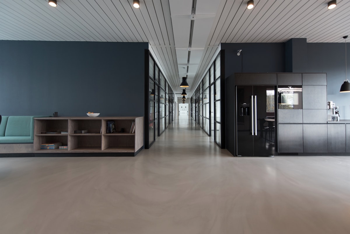 Open-plan corporate office with long desks and city views through glass walls